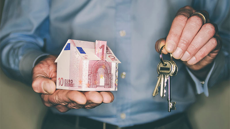 homme tenant maison en billet et cles